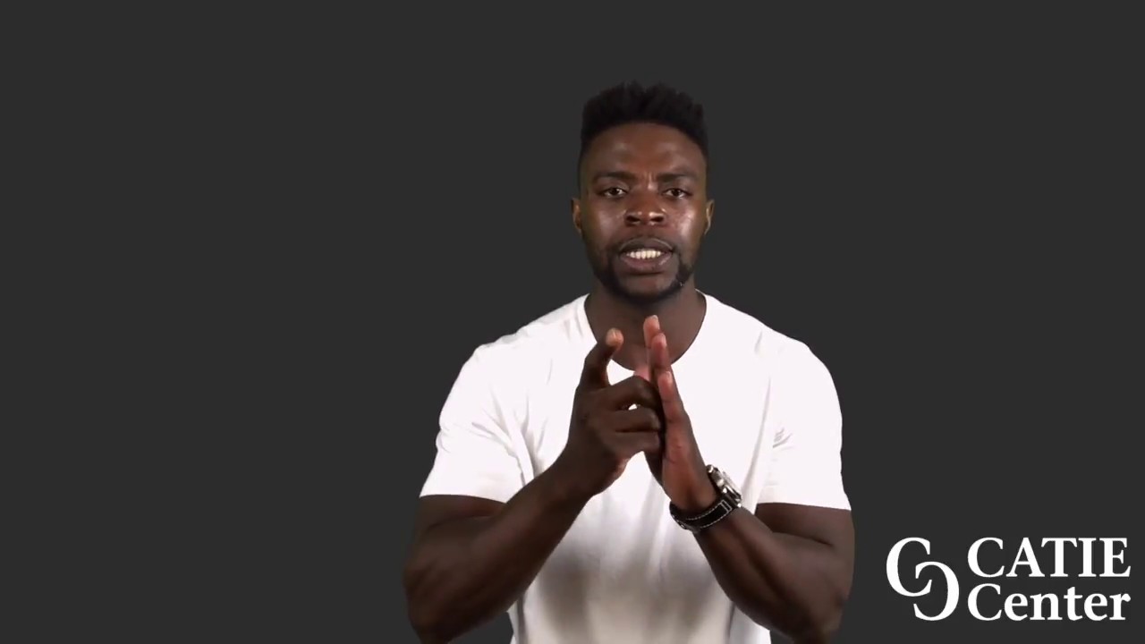 A Black man with a flattop wears a white short-sleeve t-shirt and stands in front of a dark grey background. He narrates the entire story.  In the lower right corner of the video screen is a white CATIE Center logo.