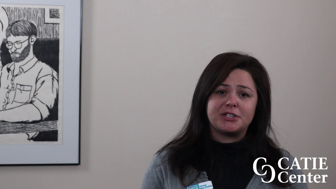 A native woman with long black hair wearing a black shirt and grey sweater speaks in front of a tan wall. The CATIE Center logo is in the lower right corner of the screen.