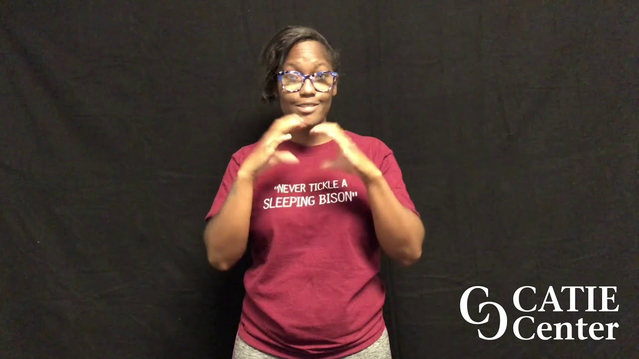 African American woman wearing horn rimmed glasses and maroon colored short-sleeve shirt that reads "Never tickle a sleeping bison" and is shown from the waist up. She is standing in front of a dark-grey screen. A white CATIE Center logo is in the lower right corner of the screen.