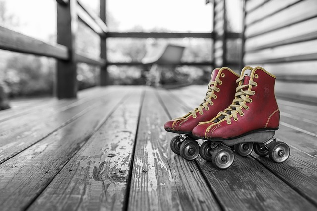 A pair of red roller skates on a grey wooden porch