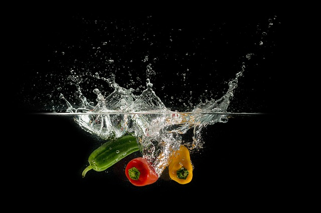 Green, red, and yellow pepper splashing into water
