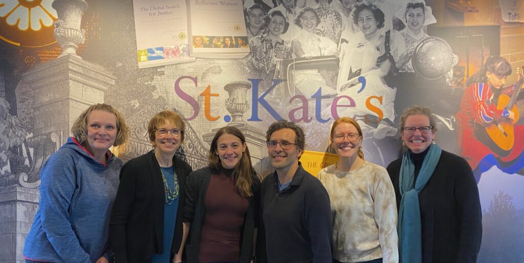 Six people stand in front of a St. Kate's mural with a combination of photographs and line drawings of campus and students