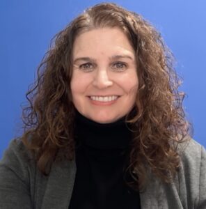 A smiling white woman with long brown, wavy hair